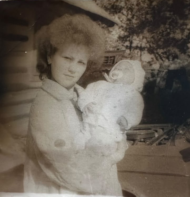 Original faded photograph of a young mother holding a newborn baby
