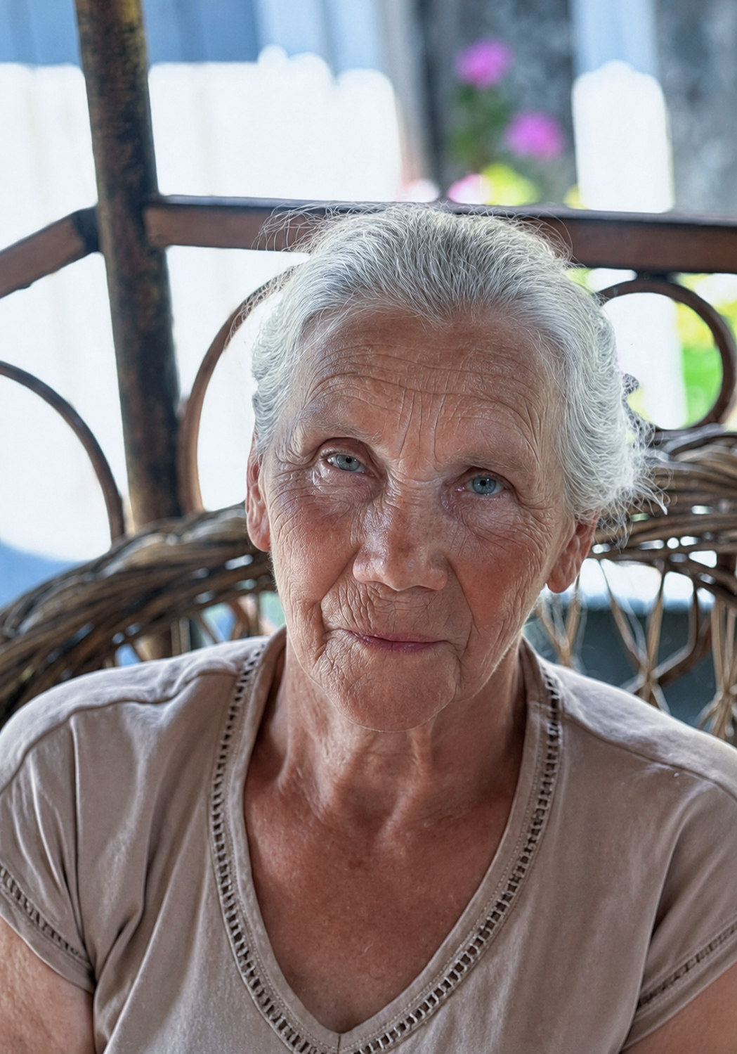 Phone photograph of an elderly woman with white hair seated in a wicker chair