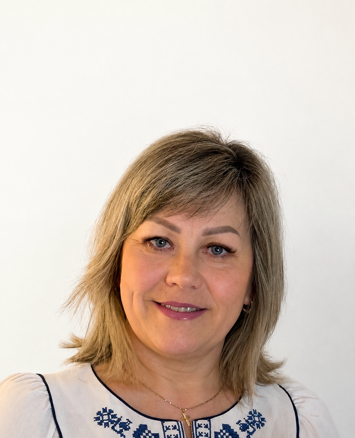 Phone photograph of a smiling woman with blonde hair in an embroidered blouse