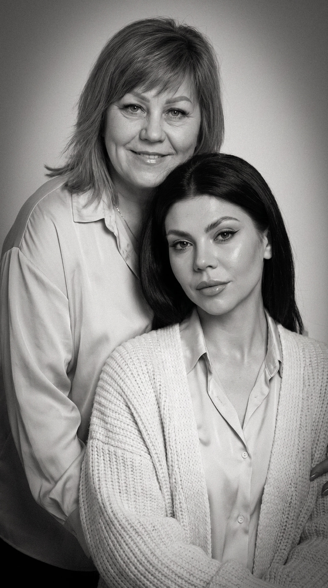 Black and white fine art portrait of a mother resting against her adult daughter