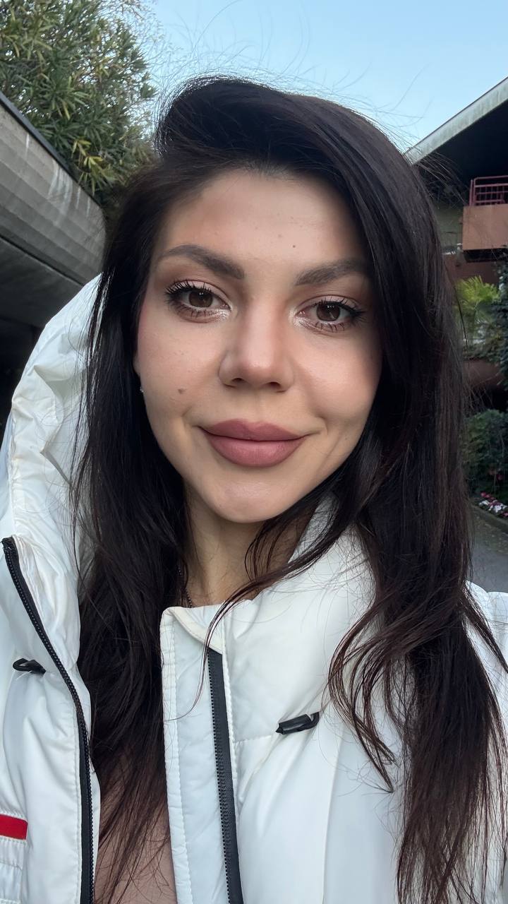 Phone photograph of a young woman in a white jacket outdoors